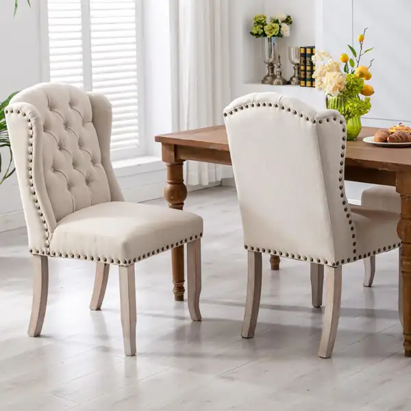 Beige tufted linen dining chairs with nailhead trim.