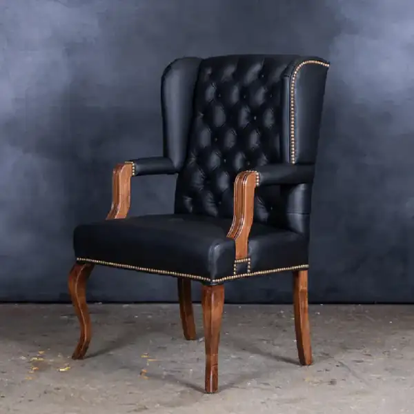 Black tufted leather armchair with brass nailhead trim.