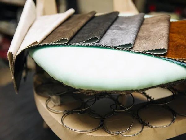 Fabric swatches on a foam chair seat with exposed springs.