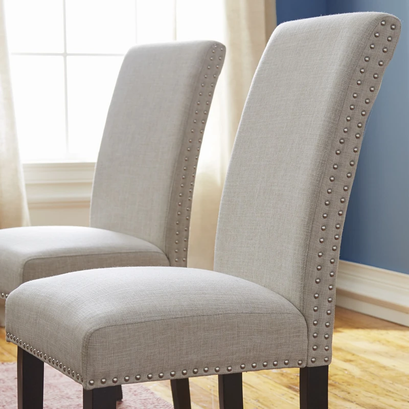 Gray fabric dining chairs with nailhead trim.