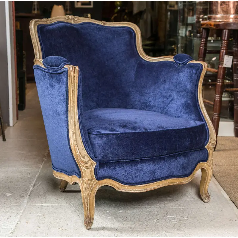 Navy blue velvet armchair with ornate gold wooden frame.