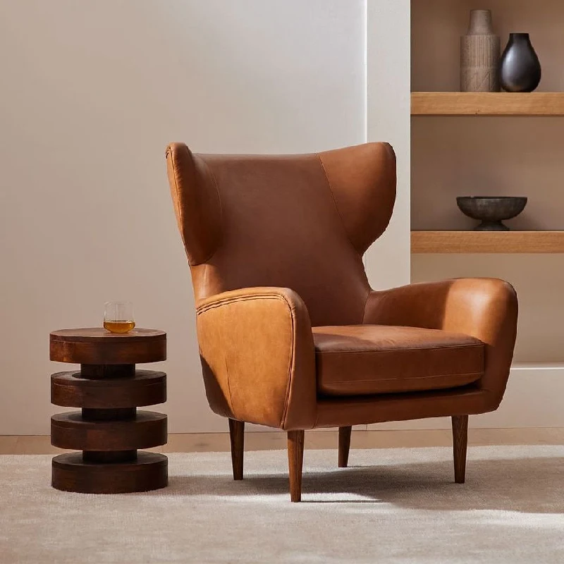 Tan leather wingback armchair with wooden legs.