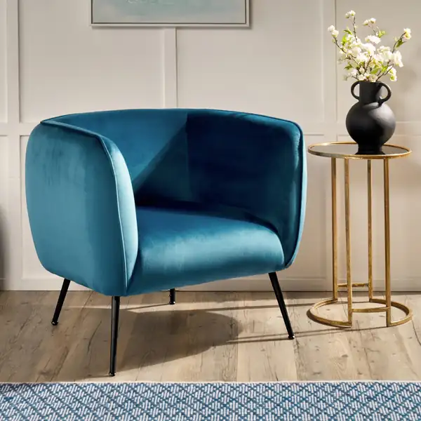Teal velvet tub chair with slender black metal legs.