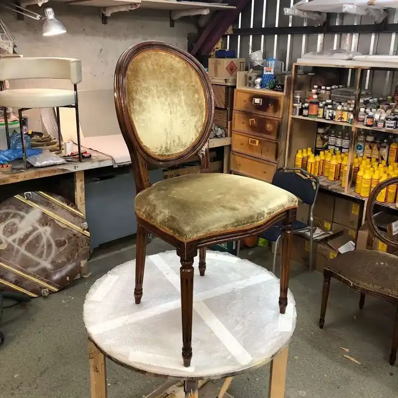 Vintage chair with olive green velvet upholstery in a workshop.